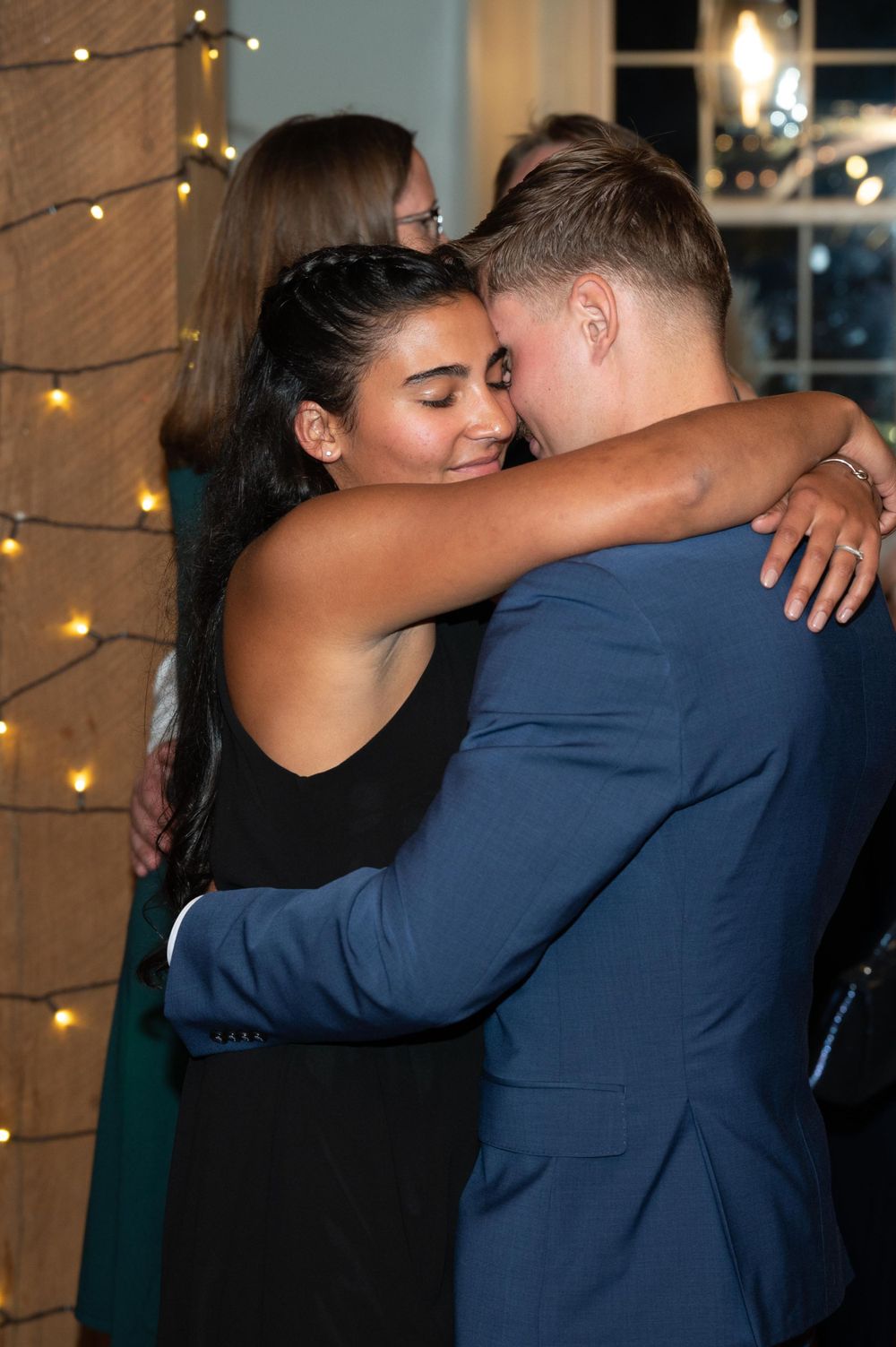 A couple sharing an intimate dance moment under string lights at an evening event.