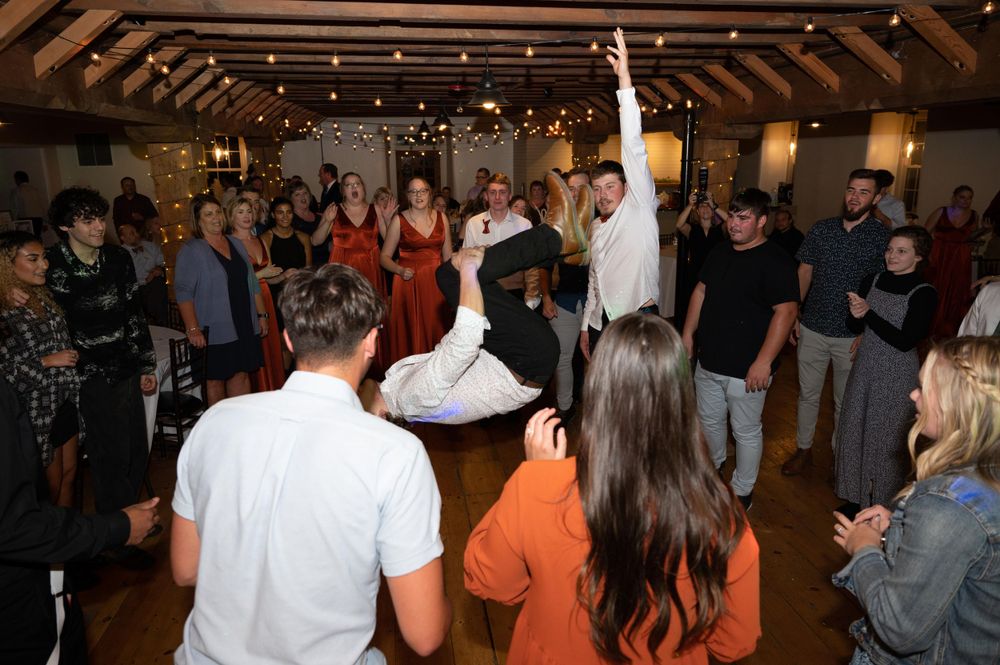 Lively dance party at a wedding reception with guests surrounding a dancing couple.