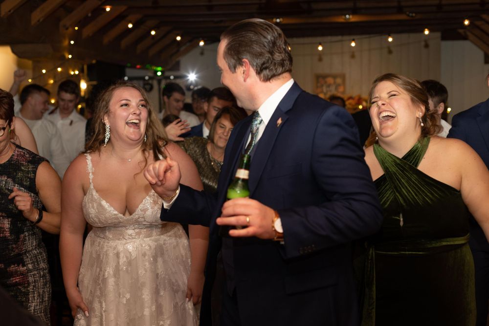 Wedding guests laughing and dancing during a lively reception celebration.