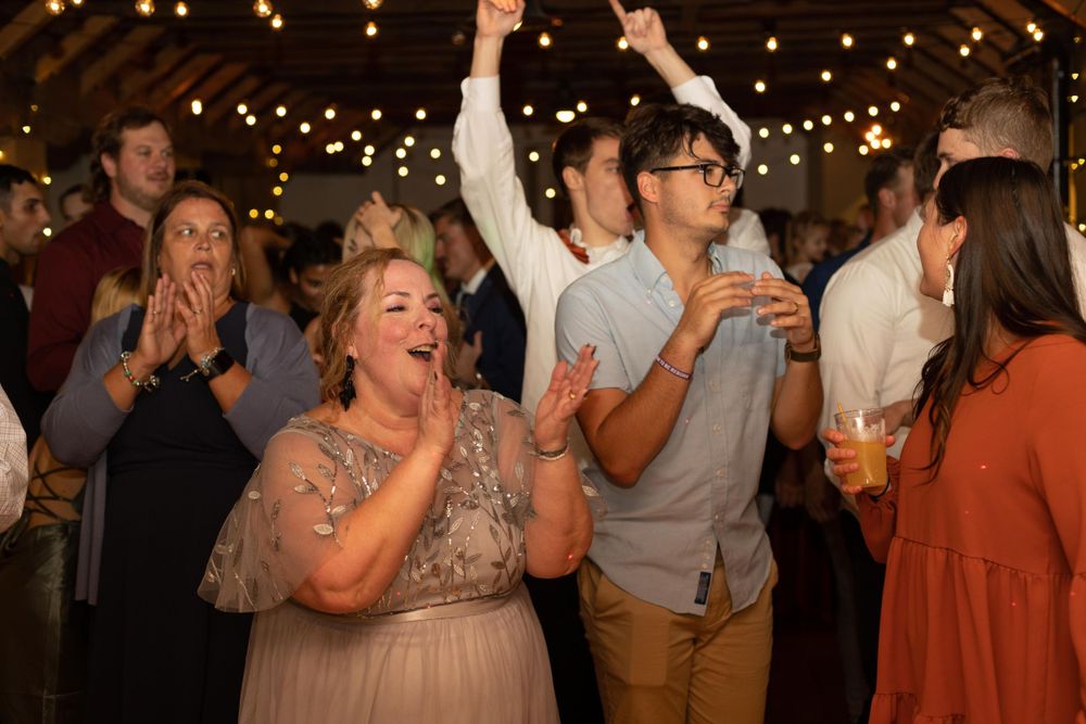 Wedding guests celebrating with enthusiastic dancing and cheering at reception.