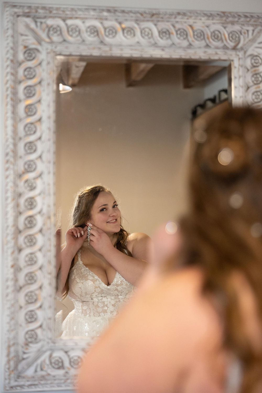 An ornate white mirror frame captures a reflection of bridal preparations.