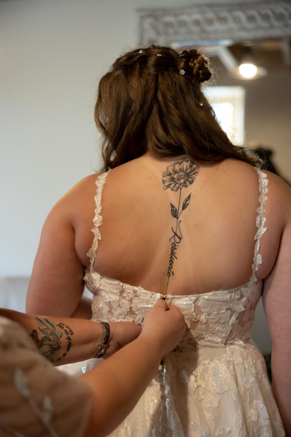 Close-up of a floral tattoo on the back of a wedding dress with delicate lace straps.