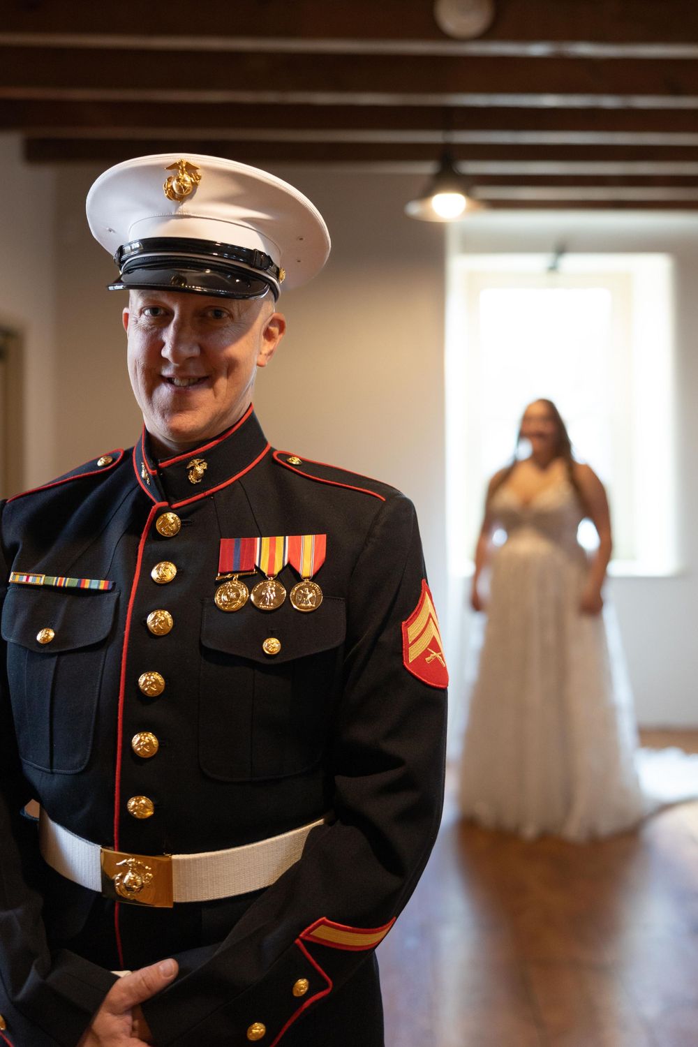 A Marine in dress blues stands proudly in his uniform with medals during a wedding first look.