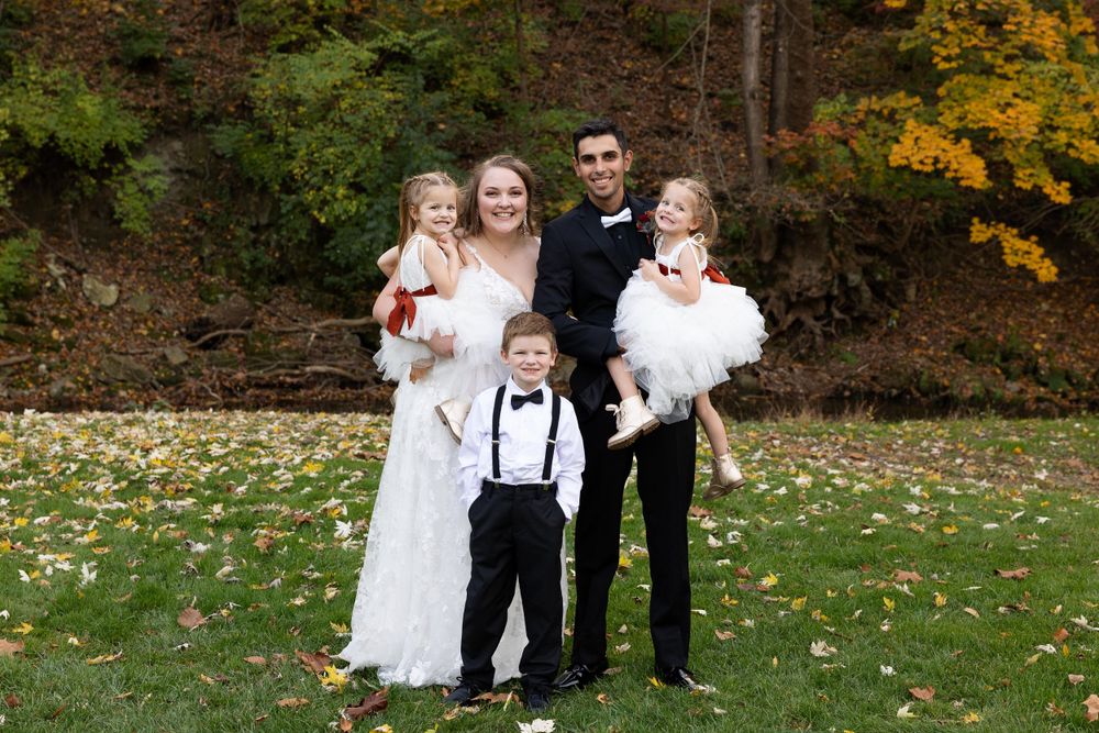 Wedding portrait with children in formal attire on autumn grass.