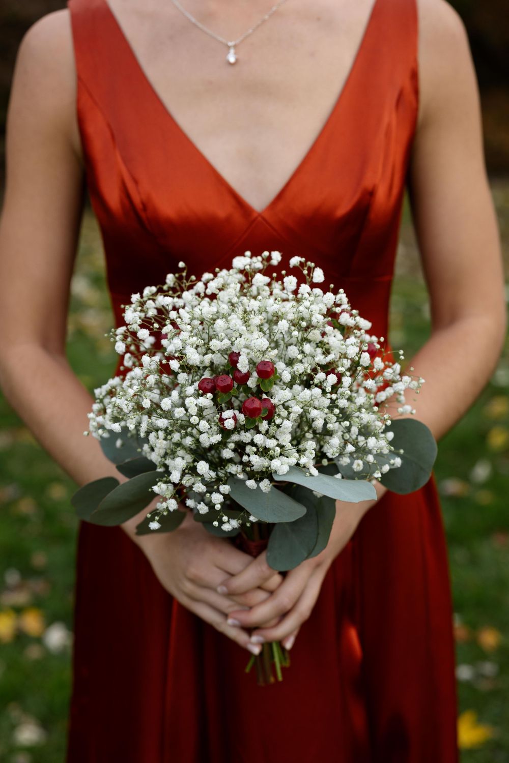 Close up of white baby's breath bouquet held against deep red bridesmaid dress.
