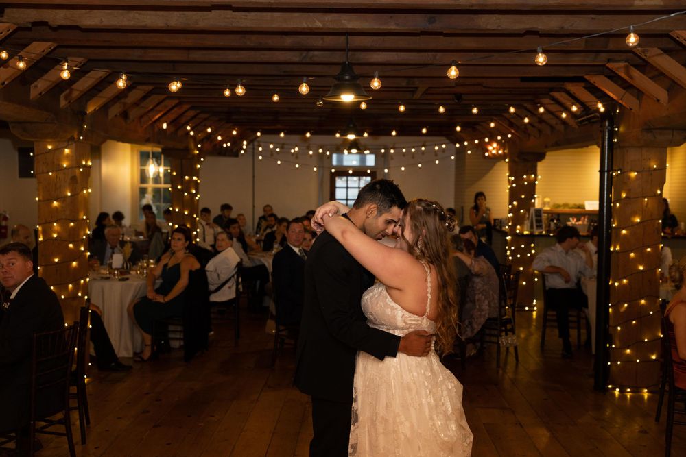First dance moment in rustic venue decorated with string lights and warm ambiance.