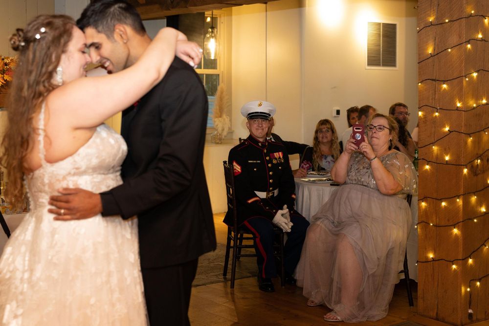 Wedding couple sharing an intimate dance while guests watch in a string-lit reception venue.