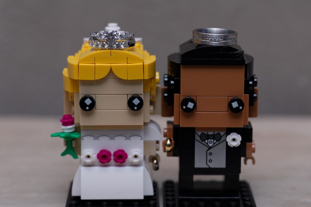 Cute LEGO bride and groom wedding cake toppers displayed against gray background.