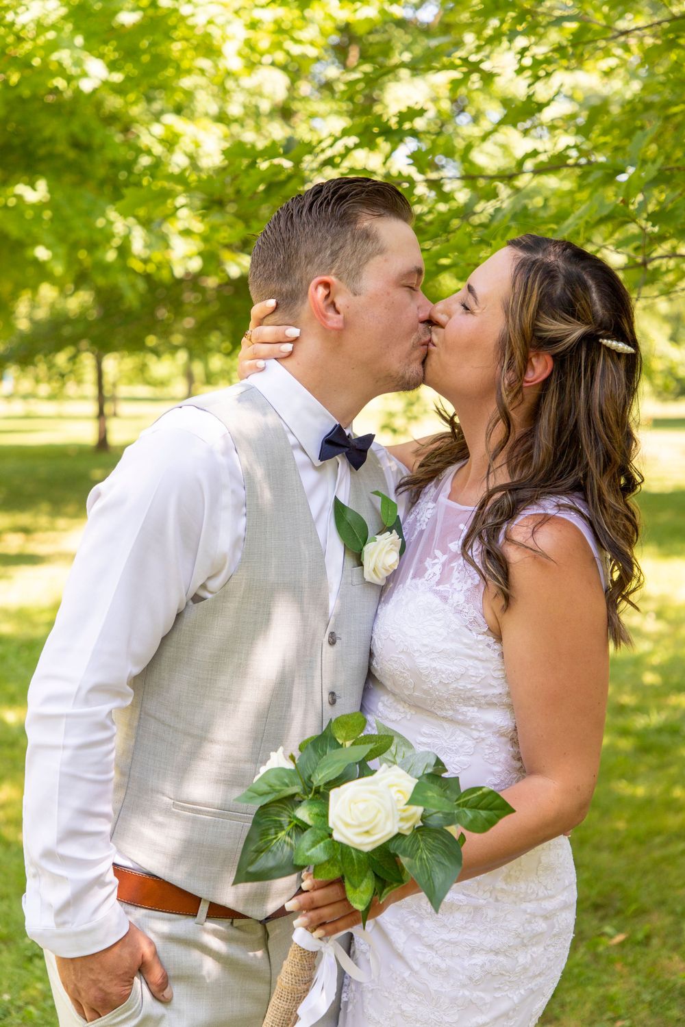 A bride grabbing the back of her grooms head to kiss him at Bowmanville Creek