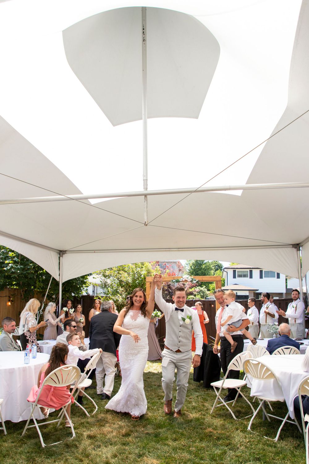 A bride and groom during their recessional under a tent at a backyard wedding in Bowmanville