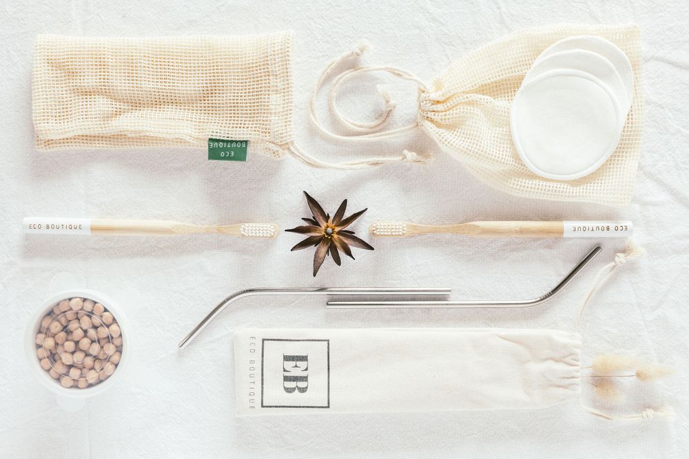 Minimalist flatlay of eco-friendly kitchen items including mesh bags and utensils on white background.