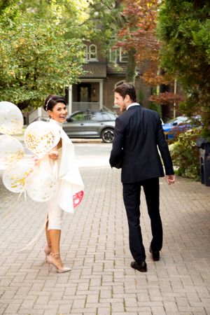 Couple walking on cobblestone path with bride carrying a vintage style parasol.