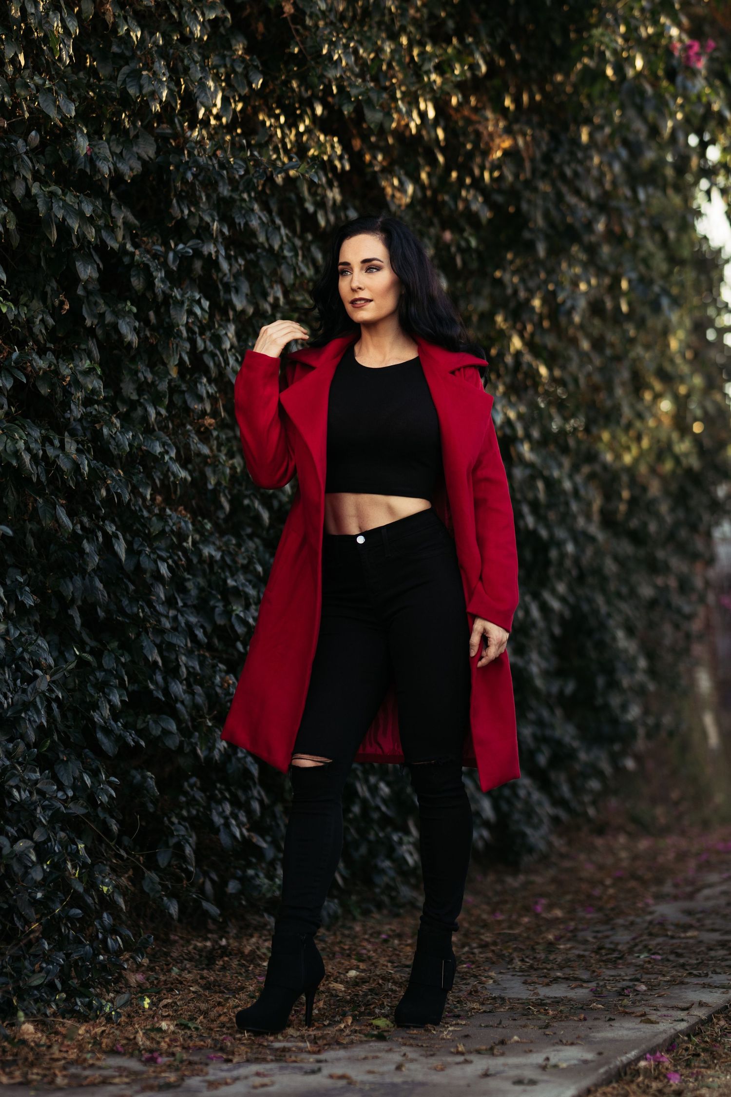 Stylish winter outfit featuring a bold red coat paired with black crop top and ripped jeans.