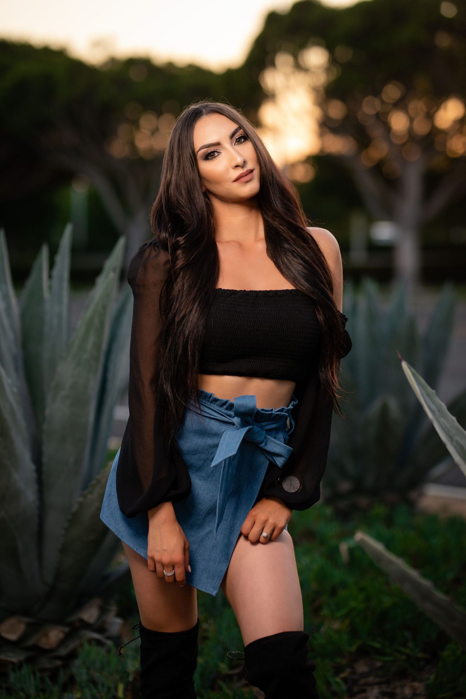 Fashion portrait in garden setting with crop top and denim skirt at sunset.