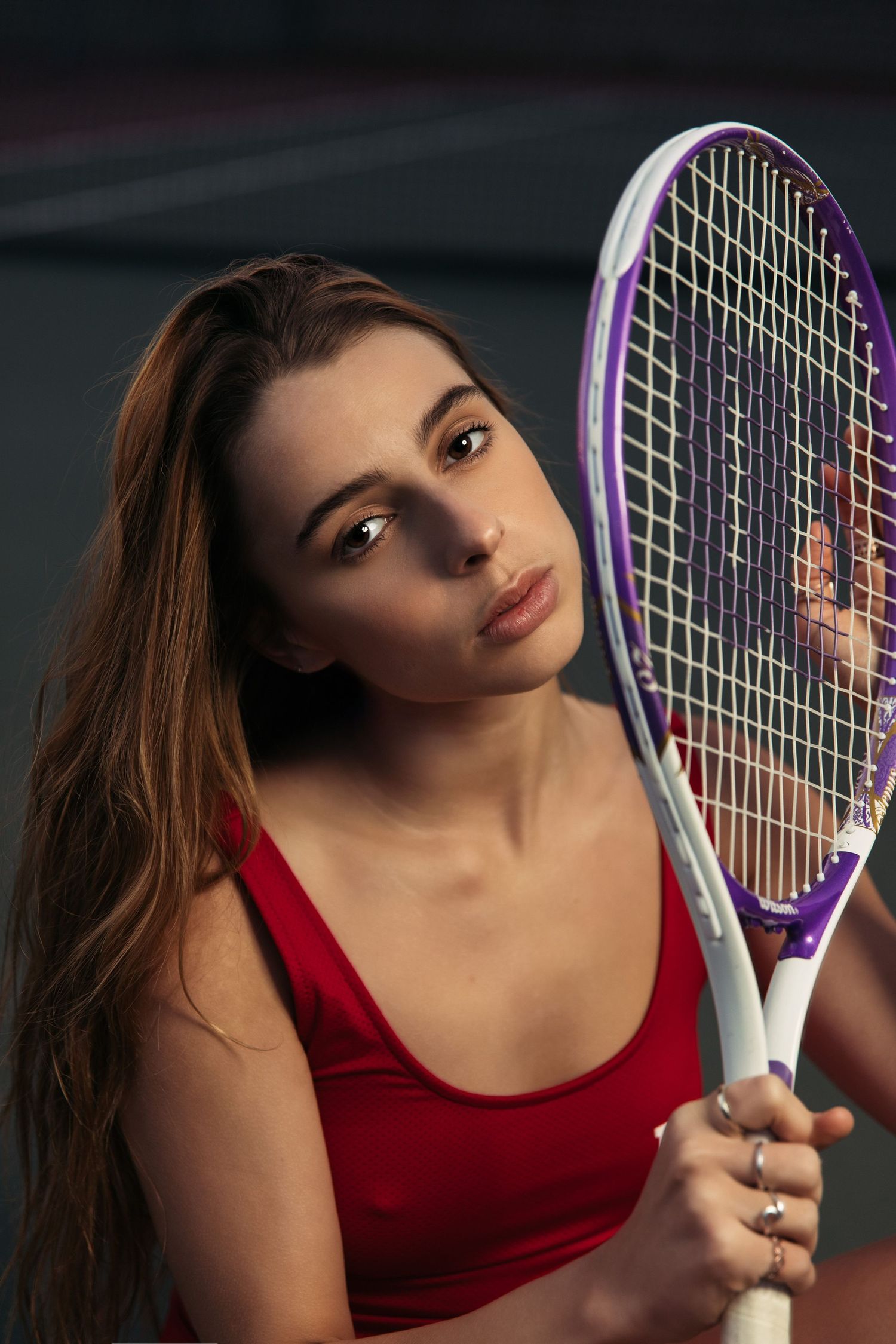 Athletic portrait with purple tennis racquet against dark background.