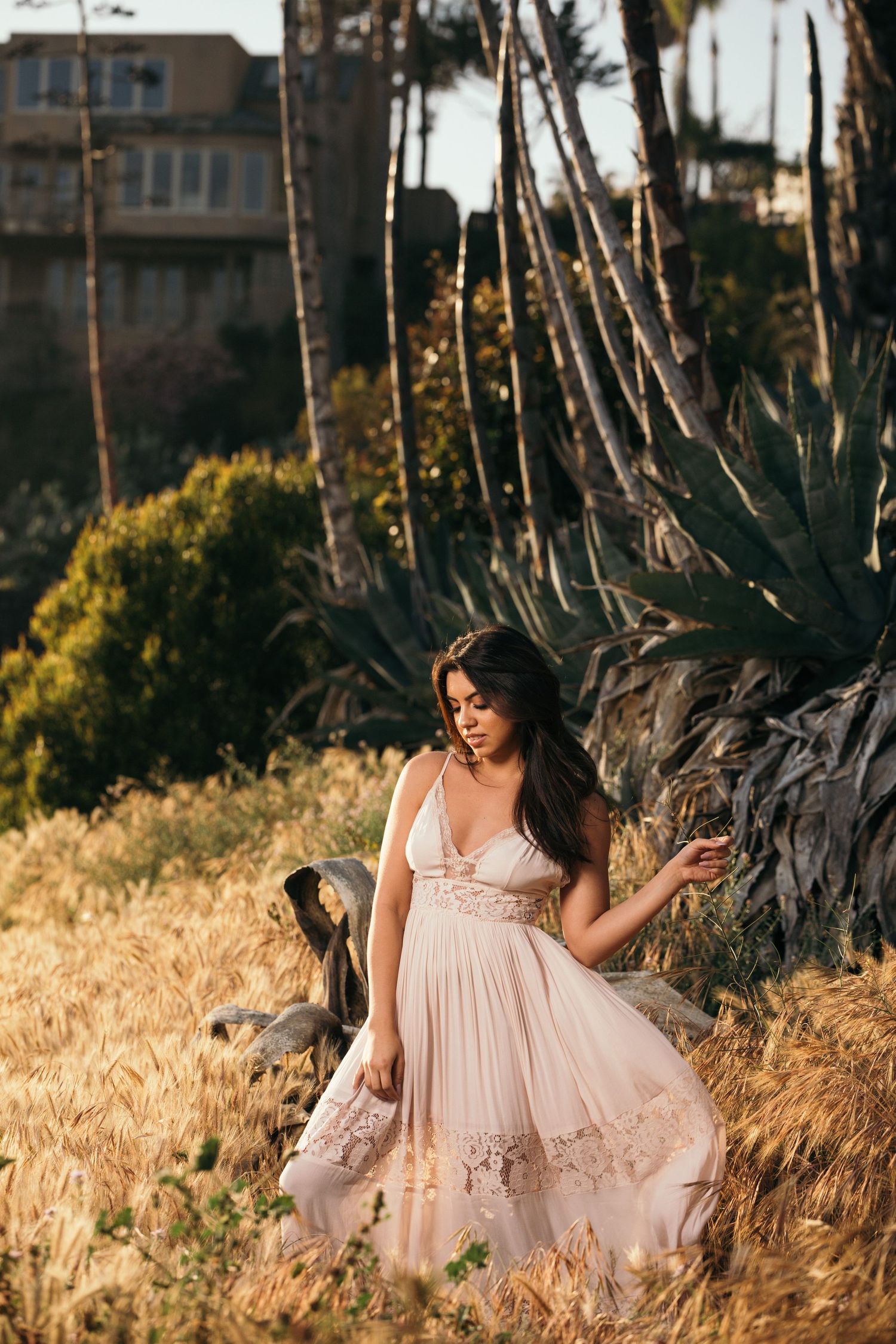 Flowing pink dress captures romantic moment in golden hour garden setting.