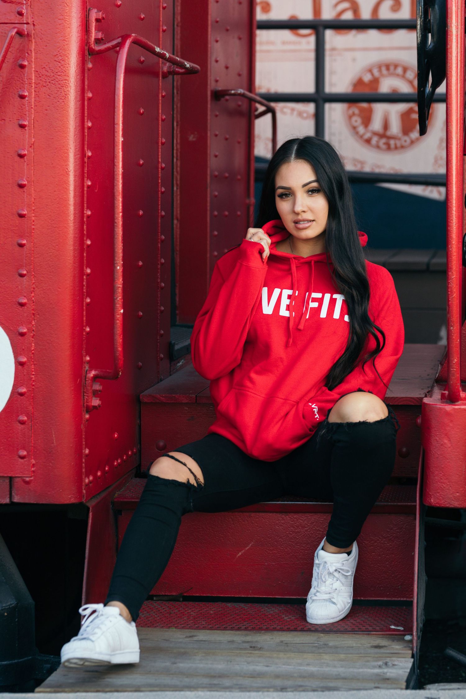 Casual street style portrait with red hoodie against industrial red background.