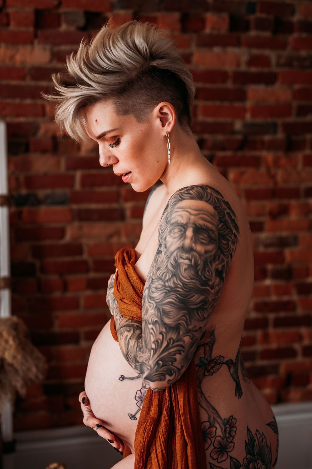 pregnant mother with tattoos posing with bare belly covered in draped cloth in home in Staten Island