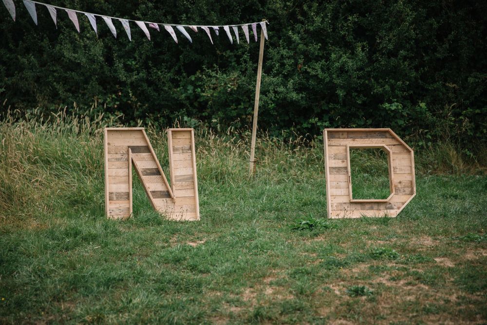 Large wooden letters N and D displayed on grass with white bunting overhead.