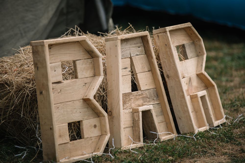 Rustic wooden letters spelling BAR with straw accents against a dark background.