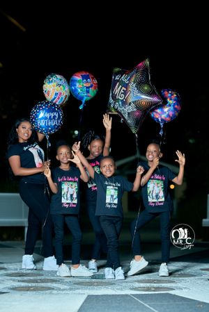 Group celebration photo with colorful birthday balloons at night.