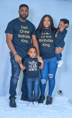 Family wearing matching navy blue birthday-themed t-shirts for celebration photo.