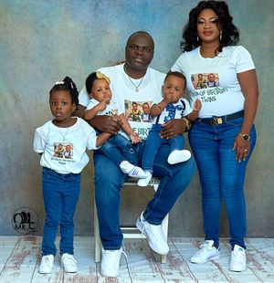 Casual family photo with matching t-shirts and jeans against light backdrop.