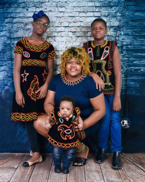 Family portrait featuring traditional African print clothing against blue brick wall.