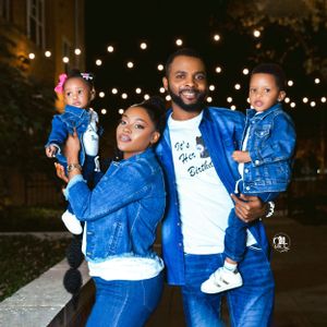 Family wearing matching denim outfits posing under string lights at night.
