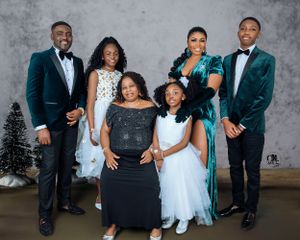 Formal family portrait with seven people in evening wear against grey background.