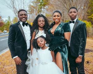Formal family portrait outdoors with members wearing elegant black and green attire.