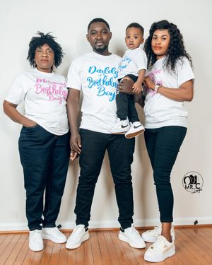 Family in coordinated white t-shirts with blue and pink text poses against white wall.