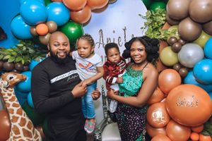 Family celebration with colorful balloon arch featuring safari theme decorations.