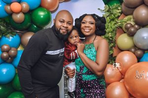 Safari-themed party scene with family posing under decorative balloon arch.