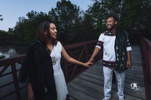 Couple holding hands on wooden bridge during twilight photoshoot.
