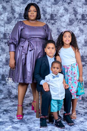 A family portrait featuring a group in coordinated outfits against a textured gray backdrop.