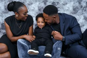 A loving family moment captured against a gray backdrop showing warmth and connection.