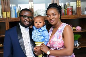 Family portrait in casual formal wear taken indoors with shelving visible in background.