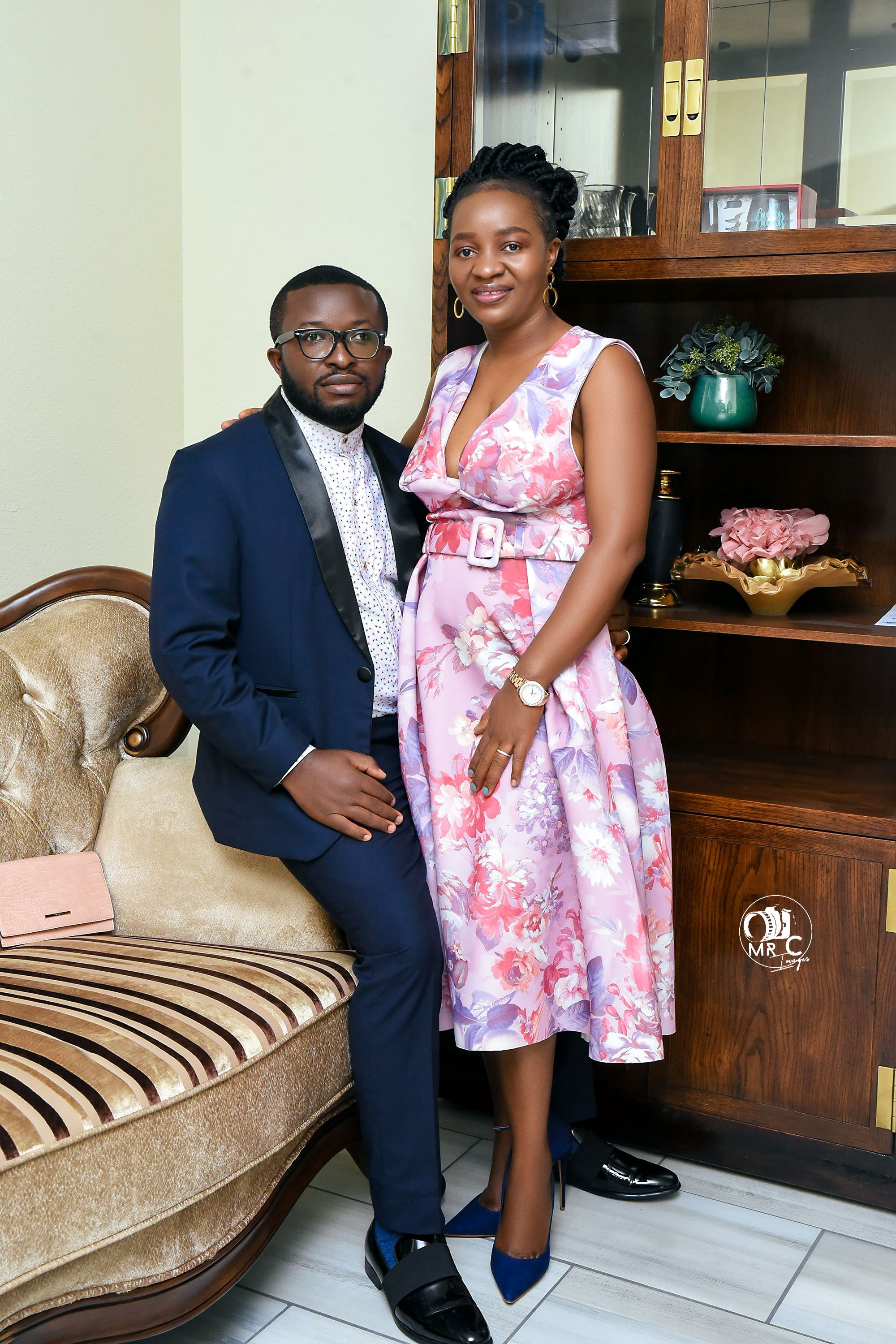 Elegant couple posing in formal attire with floral pink dress and navy suit.