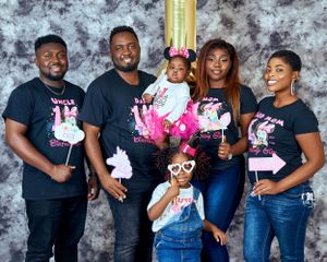 Family group photo with members wearing matching black t-shirts and fun party accessories.