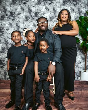 Family of five in coordinated black outfits poses for studio portrait.