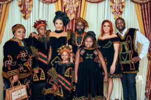Family wearing coordinated black and gold traditional African attire for formal portrait.