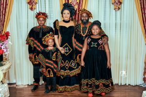 Family group wearing matching black and gold traditional African formal attire.