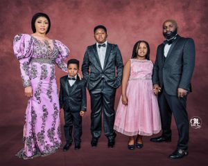 Formal family portrait with coordinating pink and purple formal wear against burgundy backdrop.