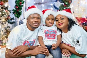 A festive family Christmas photo with matching Santa hats and t-shirts surrounded by holiday decorations.