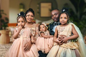 A family portrait in coordinated pink and beige outfits against an elegant interior setting.