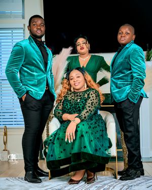Group portrait with four people in coordinating emerald green formal wear against white interior.