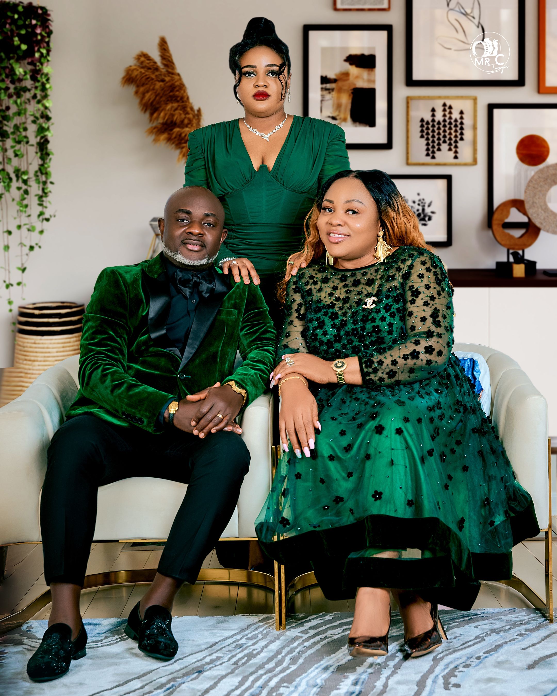 Stylish family portrait in coordinated emerald green formal wear against gallery wall.
