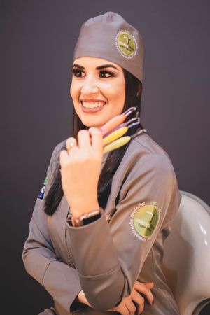 Professional wearing grey medical uniform with emblems smiling at camera.