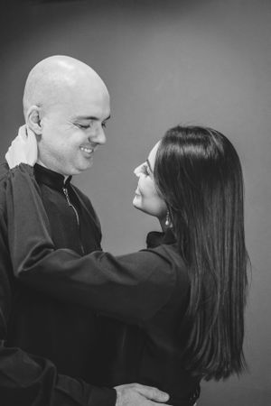Black and white portrait of couple embracing and smiling at each other.